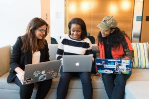 Image of three young women using laptop computers and talking